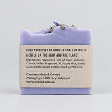 A rectangular bar of lavender soap with a textured, layered top, wrapped in a gray paper label.